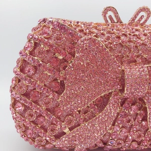 Macro shot of pink rhinestones and hollow bow clasp on metal evening clutch bag