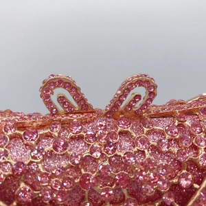 Macro shot of pink rhinestone evening clutch with hollow metal bow clasp and crystal detail
