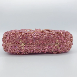 Macro shot of pink rhinestones and golden metal bow clasp on a luxury clutch bag