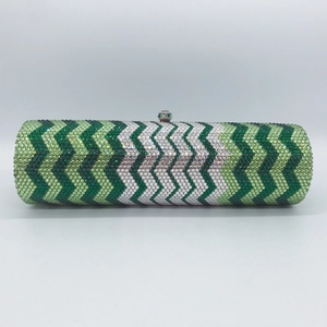 Macro shot of green wavy rhinestone patterns and metal clasp on luxury cylindrical clutch