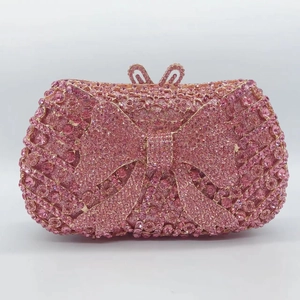 Detail of pink crystal evening clutch bag featuring a 3D rhinestone bow and metal frame