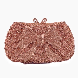Detailed close-up of rose gold bow clutch bag with sparkling hand-set rhinestones