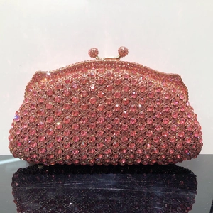 Pochette de soirée en strass roses avec cadre doré et reflet élégant sur table