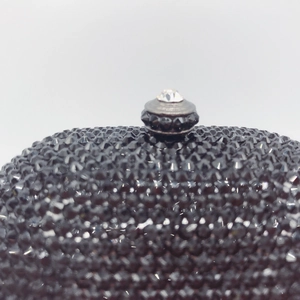 Black crystal evening bag with a large diamond-encrusted round metal clasp and chain