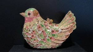 Macro detail of bird-shaped evening clutch with multi-colored crystals and gemstone eye