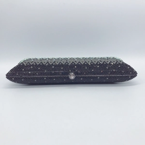 Macro view of crystal buckle and silver metal frame on black rhinestone clutch bag