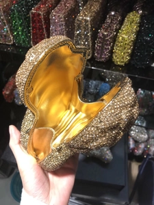Close-up of golden rhinestone clutch bag with satin lining and secure clasp detail