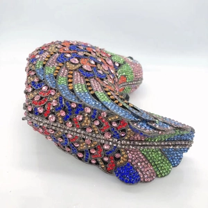 Macro detail of bird-shaped clutch showing colorful rhinestones and premium metal frame