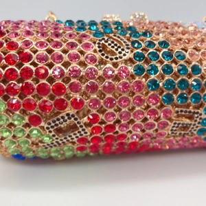 Makro-Detail bunter Strasssteine und D-Logo auf einer luxuriösen zylindrischen Clutch