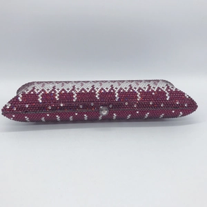 Close-up of elegant evening clutch featuring wine red and clear crystal wave patterns