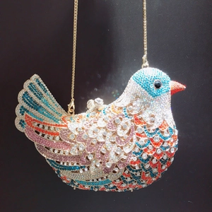 Macro detail of bird-shaped clutch showing colorful rhinestones and gold chain