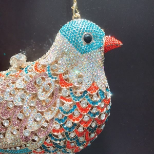Macro detail of bird-shaped evening bag with colorful crystals and gold metal clasp