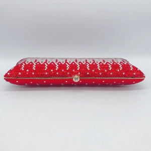 Detailed view of red and white rhinestones on a long evening clutch with gold clasp