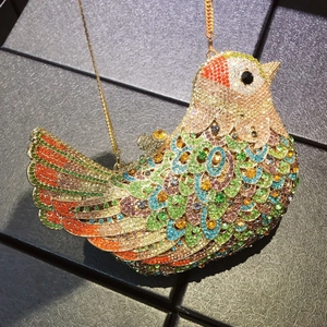 Detail of bird shaped evening clutch with colorful rhinestones and gold chain