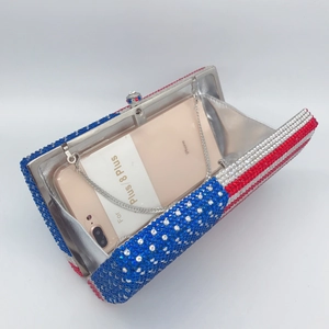 Detail of evening clutch bag showing open silver interior holding a large smartphone