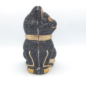 Cat-shaped evening clutch bag with black and gold crystals on a minimalist background