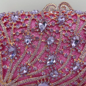 Gros plan d'une pochette rose pailletée avec motifs dorés et strass violets
