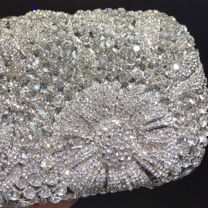 Macro view of sparkling rhinestones and crystal bow detail on silver evening clutch bag