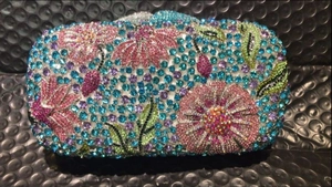 Macro shot of colorful floral crystal encrusting on a luxury metal hard-shell clutch bag