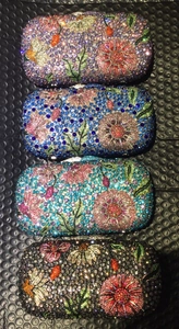 Four floral crystal evening clutch bags in purple, royal blue, green, and black