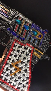 Macro shot of colorful rhinestones on a unique pistol shaped sparkling evening clutch bag