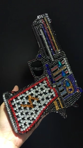 Detailed view of novelty handgun shaped clutch bag with colorful rhinestones in hand