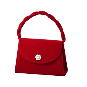 Macro shot of red velvet wedding handbag with camellia pearl buckle and twisted handle