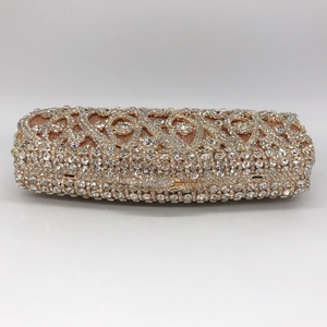 Detail of the champagne rhinestone scrollwork on the metallic frame of the evening clutch bag