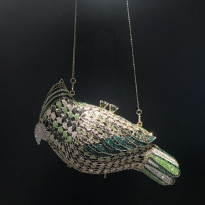 Detailed close-up of a luxury bird-shaped evening clutch bag with green and white rhinestones