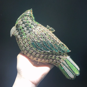 Macro shot of bird-shaped clutch bag with emerald and crystal rhinestone pavé detailing