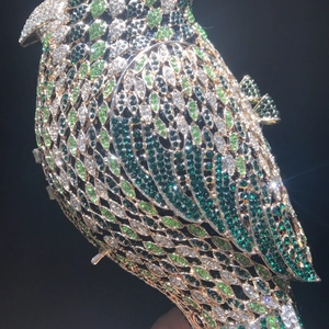 Detail shot of a bird-shaped clutch bag encrusted with green and white rhinestones