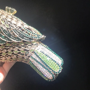 Macro shot of luxury evening clutch bag featuring intricate green bird rhinestone detail
