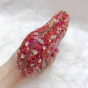 Detail of evening clutch featuring red crystal floral scroll patterns and gold clasp