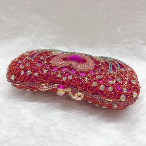 Detail of luxury rhinestone evening clutch featuring vintage patterns and a pink heart crystal