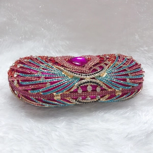 Detailed close-up of crystal evening clutch with heart gemstone and peacock feather pattern