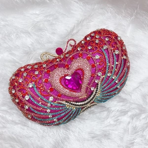 Detail of luxury crystal evening clutch with pink heart gem and peacock wing accents