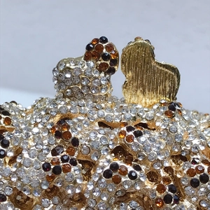 Close-up of golden popcorn clutch with white and amber rhinestones and bear detail