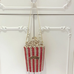 Close-up of popcorn-shaped clutch with red and white crystal stripes and gold chain