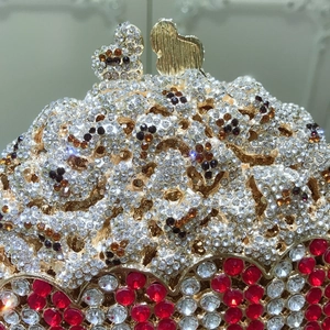Close-up of golden hollow evening clutch with intricate crystal pavé and red rhinestones