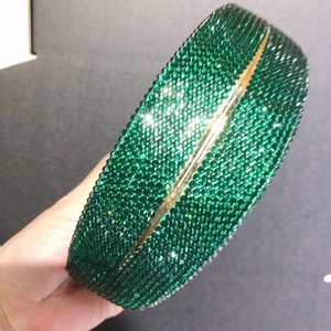 Detailed close-up of emerald green crystal evening clutch with gold metal frame