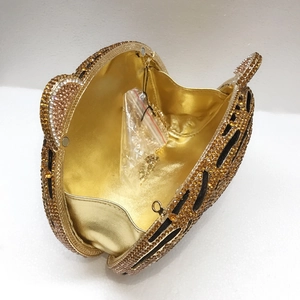 Macro detail of gold rhinestone evening bag interior with luxury metallic lining and chain