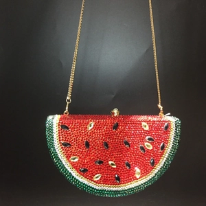 Detailed view of watermelon crystal clutch with red rhinestones and gold chain strap