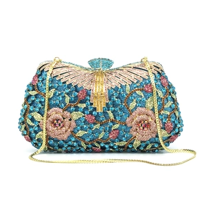 Detail of royal blue evening clutch featuring rhinestone flowers and peacock clasp