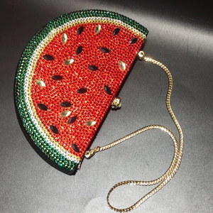 Macro detail of watermelon-shaped clutch with sparkling red and green crystals and chain