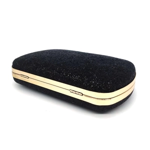 Detail of black sequin clutch bag showing gold metal frame and sparkling glitter texture