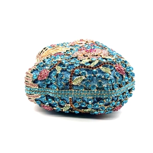 Detailed side view of floral rhinestone evening bag with pink crystal flowers and gold metal trim