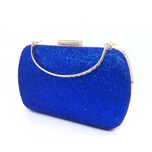 Close-up of royal blue sequined evening clutch with gold metal frame and semi-circular handle