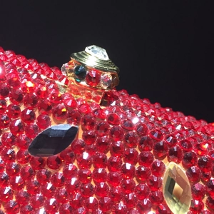 Close-up of red crystal watermelon clutch featuring handset rhinestones and gold clasp