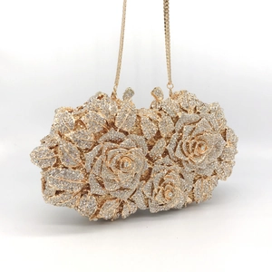 Close-up of luxury gold evening clutch featuring 3D rose pattern with white rhinestones