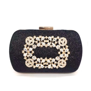 Detail of black sequin evening bag featuring gold metal cutout with white rhinestones